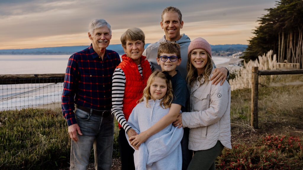 Rowan, a young girl with Fragile X syndrome, standing with her family at a scenic outdoor location, symbolizing love and support.