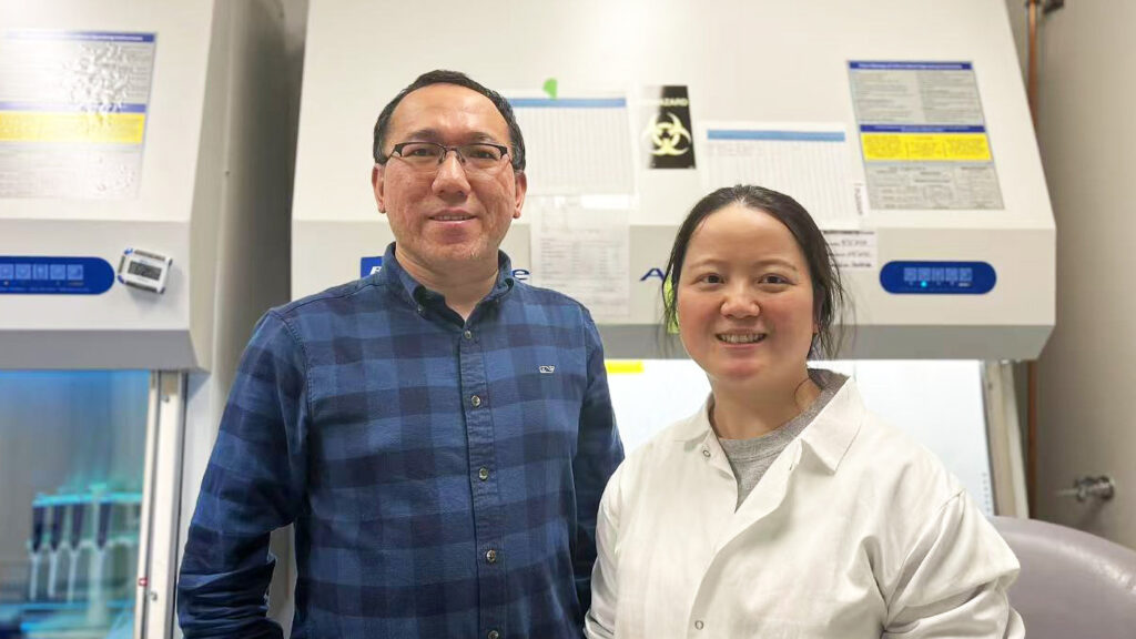 Ziyuan Guo, PhD, and Lu Lu, PhD, standing together in a research lab with laboratory equipment in the background.