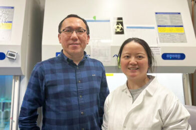 Ziyuan Guo, PhD, and Lu Lu, PhD, standing together in a research lab with laboratory equipment in the background.