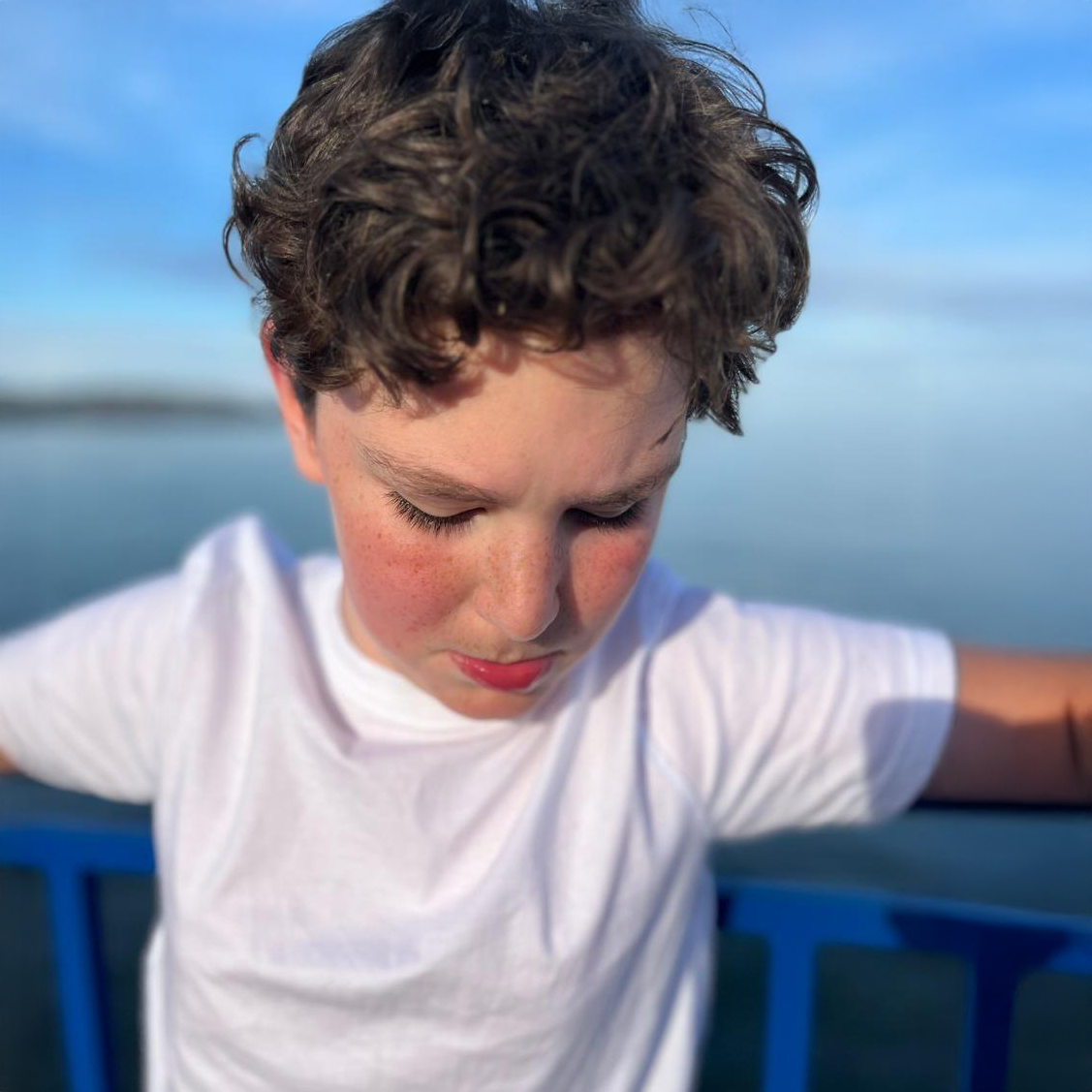 Gael Centellas looking down while standing outdoors, part of a family in the Fragile X community.