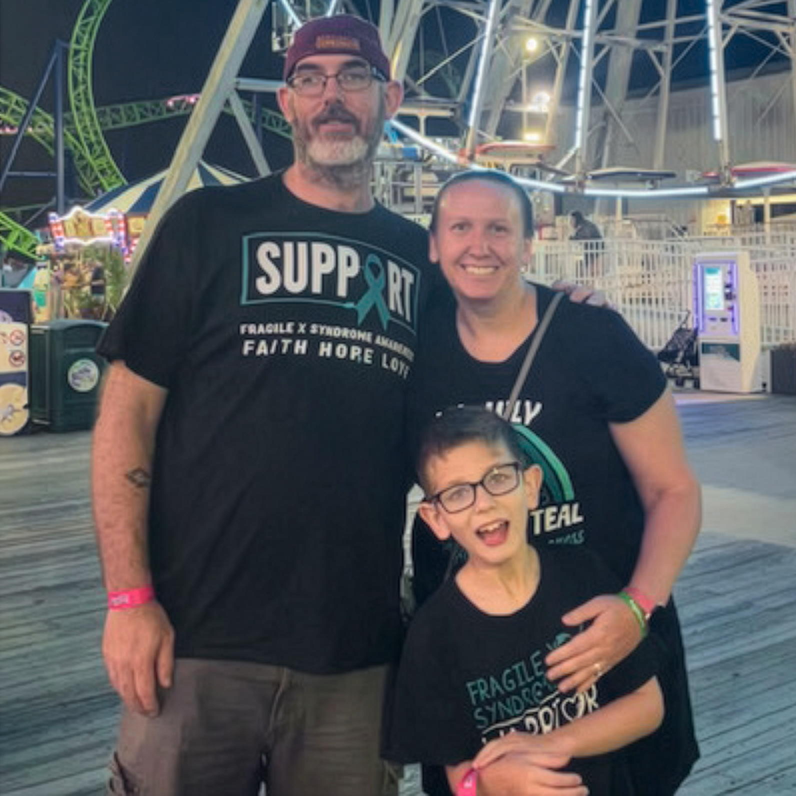The Prongay family smiling together at an amusement park, part of the Fragile X community.