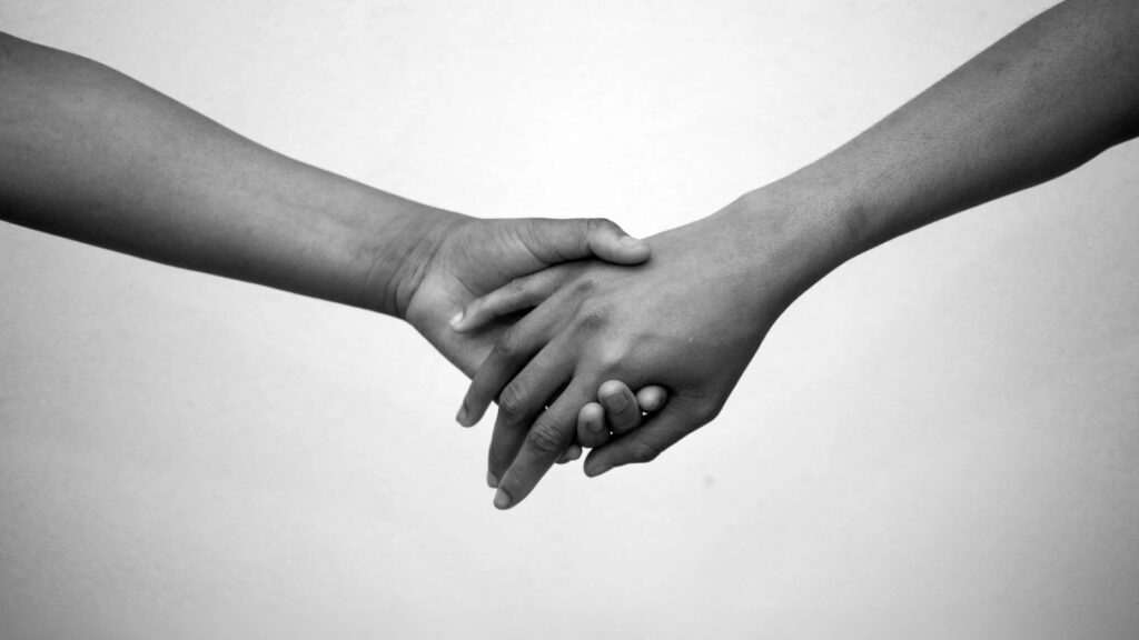 Two people holding hands, symbolizing a research partnership.